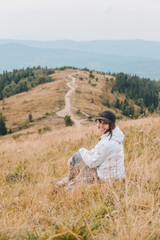 Wall Mural - woman sitting on the ground looking at mountains hiking concept