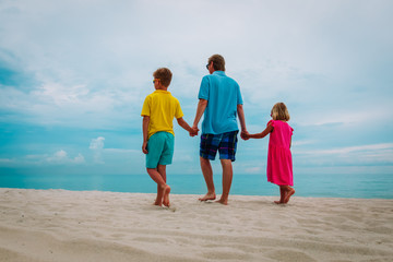 father with son and daugther walking on beach