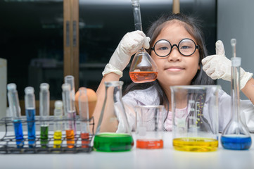 Wall Mural - happy little girl wearing lab coat making experiment