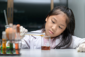 Wall Mural - happy little girl wearing lab coat making experiment