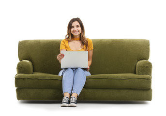 Canvas Print - Young woman with laptop sitting on sofa against white background