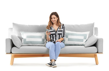 Canvas Print - Young woman with mobile phone sitting on sofa against white background