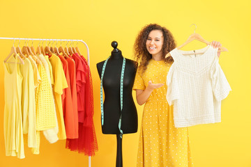 African-American stylist near mannequin and rack with modern clothes