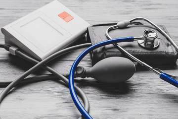 Stethoscope with sphygmomanometer on grey wooden background