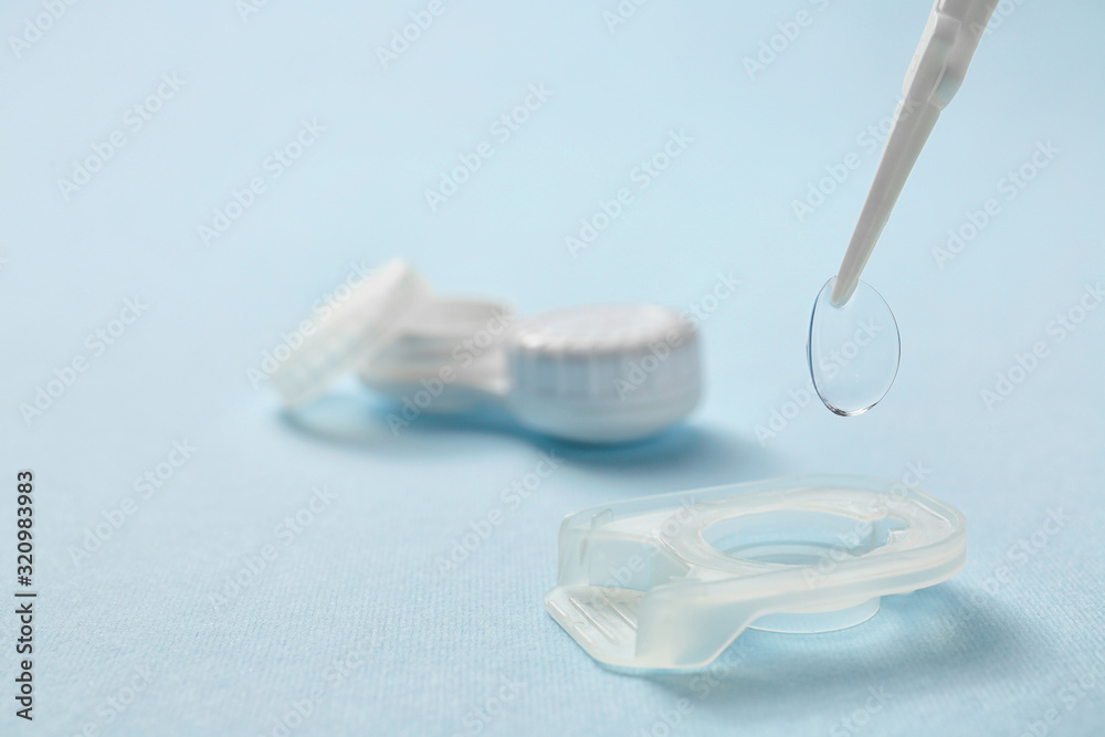 Taking of contact lens from case on color background, closeup
