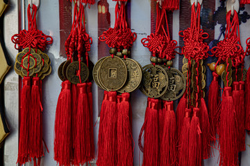 East Asian symbol of luck. Traditional Chinese souvenirs made from antique copper coins and red woven yarn decorations with long tassels. Retail display of oriental gifts for Lunar New Year.