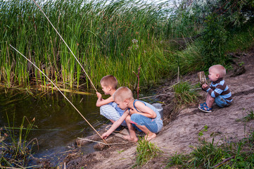 Funny children in colorful clothes took fishing rod and try to fish near river in the reeds. Funny situations while fishing. Summer vacation in village. Brothers are happy together