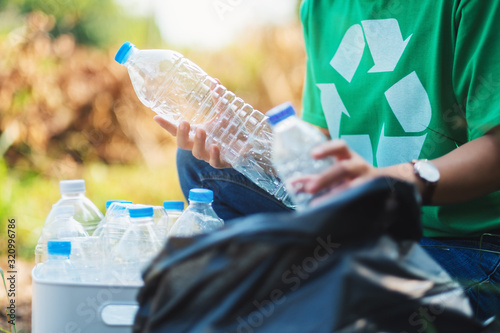 Fotomural A woman picking up garbage plastic bottles into a box and bag for recycling conc