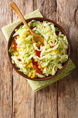 Wall Mural - Fresh salad of savoy cabbage with corn, onions and bell pepper close-up in a bowl. Vertical top view