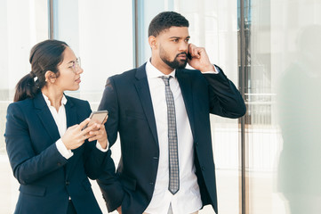 young successful business people using smartphones outdoors. young woman in formal suit holding her 