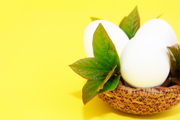 Wall Mural - white eggs and green leaves in a decorative straw plate for Easter