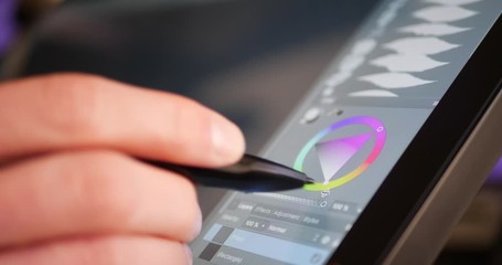 a freelance digital artist or designer selecting a color hue and painting with a drawing graphic tab