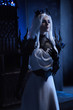 Attractive blonde woman in fantasy costume of dark queen sitting on throne in castle