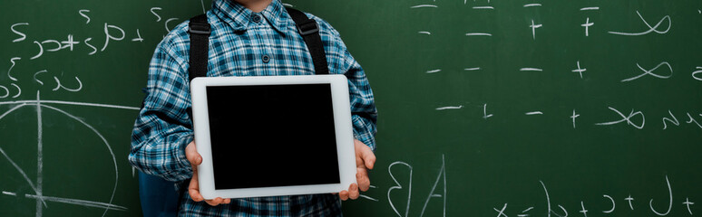 Wall Mural - panoramic shot of smart kid holding digital tablet with blank screen near chalkboard with mathematical formulas