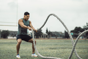 Man doing workout using battle ropes on the ground