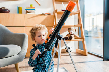 Wall Mural - smart child touching telescope near armchair at home