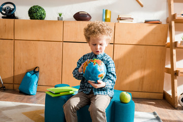 Wall Mural - smart child holding globe while sitting near books and apple