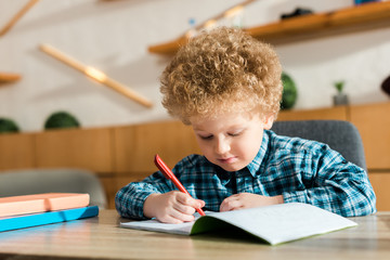 Wall Mural - smart child writing in notebook near books on table