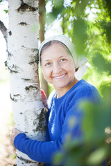 Poster -  beautiful mature woman near birch trees in summer.