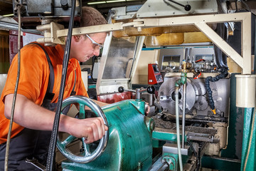 A skilled worker in the metalworking industry working on a lathe