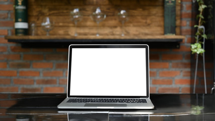 mockup laptop with white blank screen putting outdoors on the modern table with classic kitchen bar 