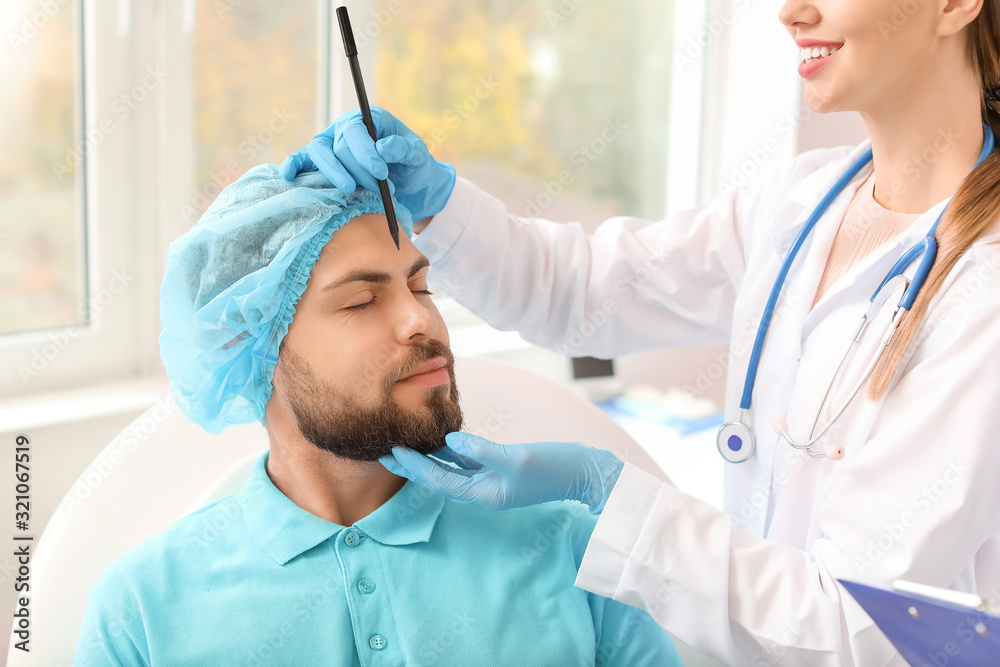 Plastic surgeon applying marks on patient's face in clinic