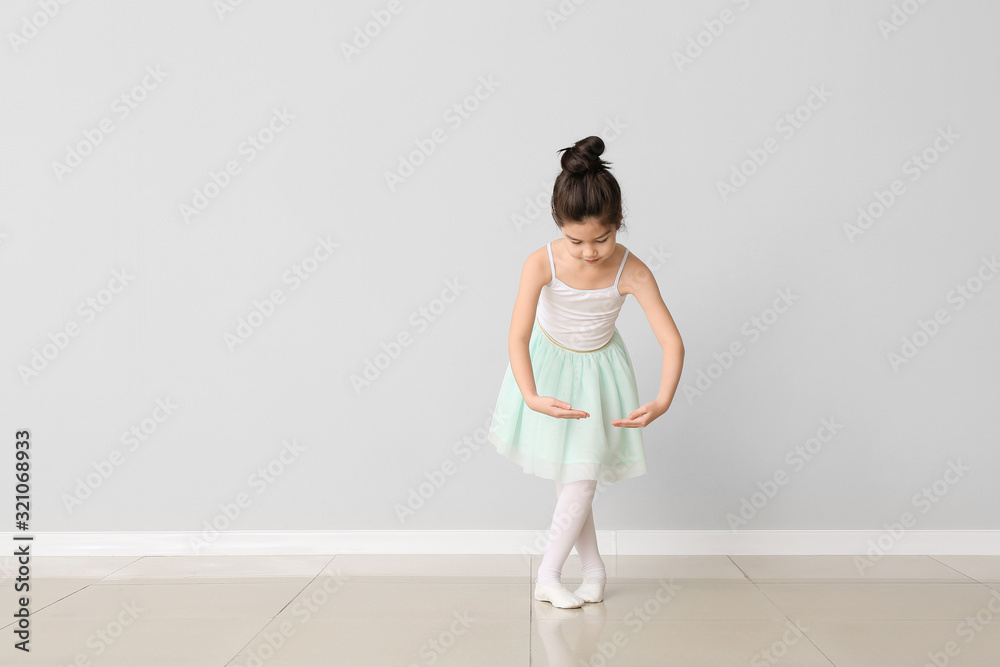 Cute little ballerina against light wall