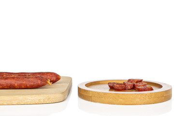 Wall Mural - Group of three whole lot of slices of piquant smoked sausage on bamboo cutting board on round bamboo coaster isolated on white background