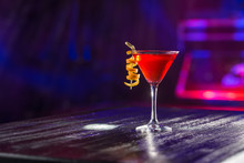 Red Cosmopolitan Cocktail With Orange Peel On The Table On Nightclub Background