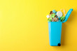 Recycle bin with trash on yellow background, space for text
