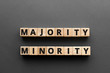Majority minority - words from wooden blocks with letters, majority minority concept, top view gray background