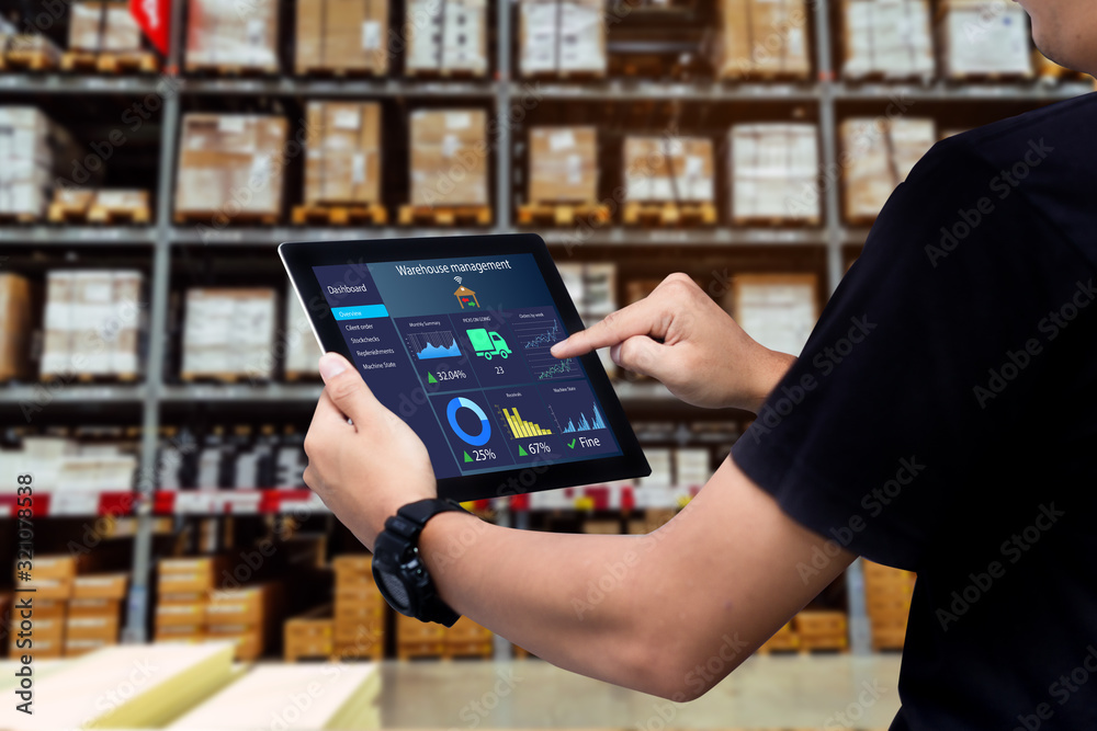 Smart warehouse management system.Worker hands holding tablet on blurred warehouse as background - obrazy, fototapety, plakaty 