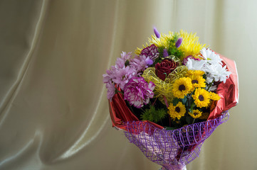 Flowers of different colors  in the bouquet on the background of green curtain. Rose, chrysanthemum, aster, carnation