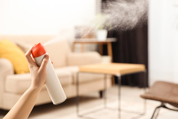 Poster - Woman spraying air freshener at home, closeup