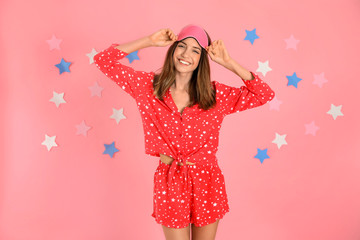 Poster - Beautiful woman wearing pajamas and sleep mask on pink background. Bedtime