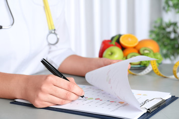 Poster - Female nutritionist with list of products at table, closeup