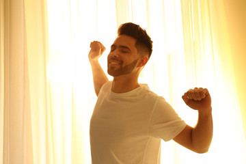 Canvas Print - Young man stretching near window at home. Lazy morning