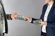 Woman giving bribe money to man on grey background, closeup