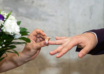 Wall Mural - The bride and groom on their wedding day exchange wedding rings.