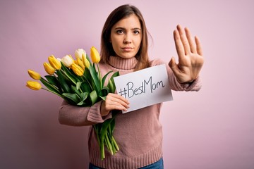 Sticker - Beautiful woman holding paper with best mom message and tulips celebrating mothers day with open hand doing stop sign with serious and confident expression, defense gesture