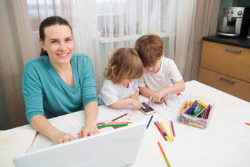 woman trying to work while babysitting two kids at home. Side hustles at home. 