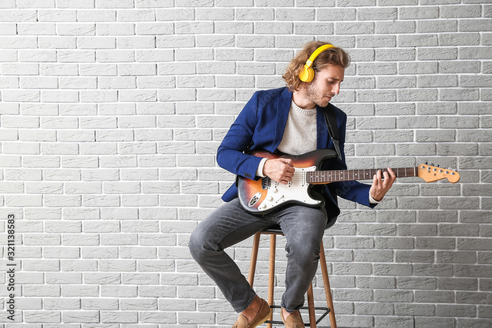 Man playing guitar against brick wall