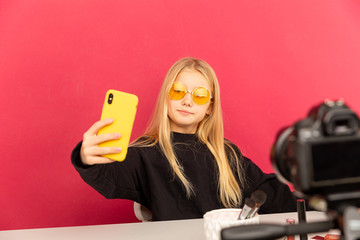 Wall Mural - Happy girl at home speaking in front of camera for vlog. Teenage kid working as blogger, recording video tutorial for Internet