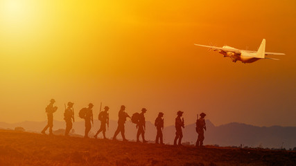 Wall Mural - Silhouette of military rangers and Helicopter with soldier on the top of mountain at sunset	
