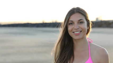 Wall Mural - Portrait of girl on the beach at sunset turn to the camera with blurred background. Slow motion.