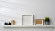 © bongkarn - Close up view of mock up frames, camera and decorations on white shelf with white wall background