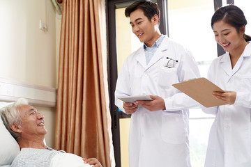 Canvas Print - two young asian doctors talking old man at bedside