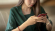 © bongkarn - Cropped shot of businesswoman using smartphone in blurred simple office room background