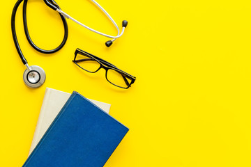 Wall Mural - Medical books near stethoscope on yellow background top-down copy space