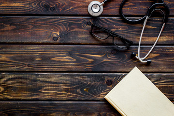 Wall Mural - Medical books near stethoscope on dark wooden background top-down copy space